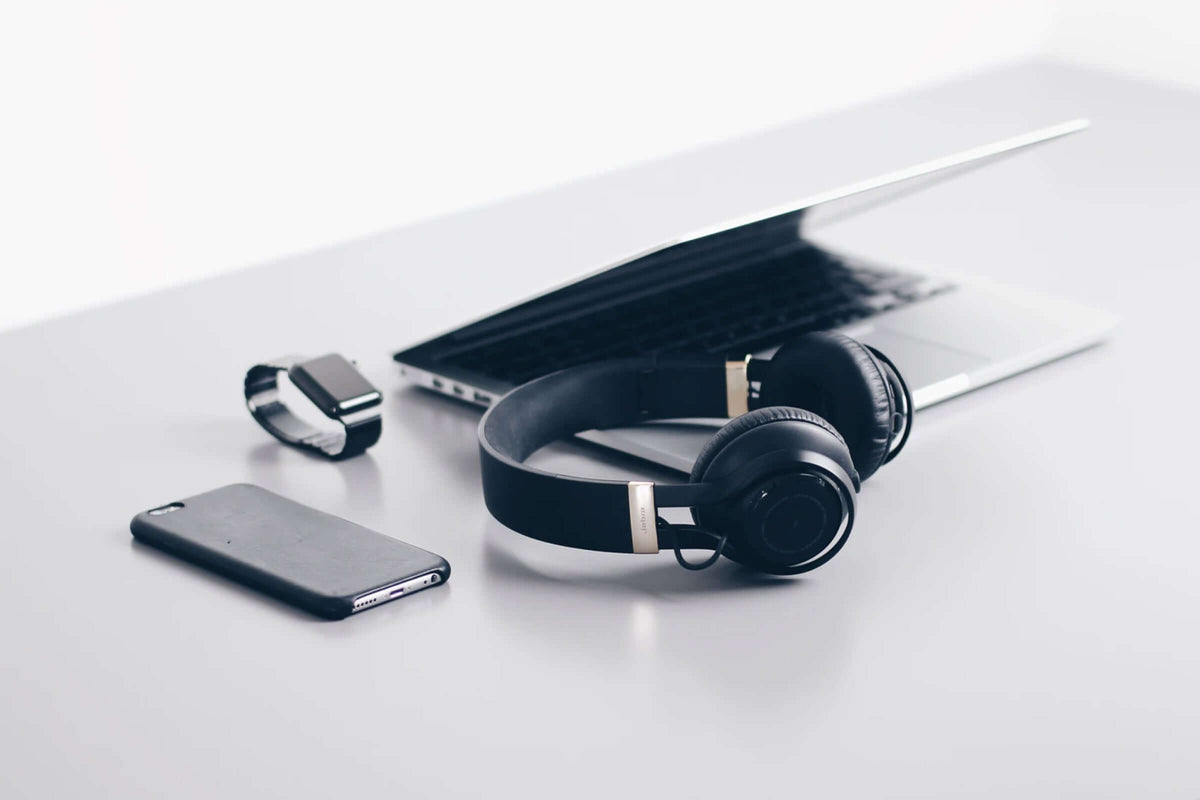Latest electronics gadgets including headphones, laptop, smartphone, and smartwatch on a modern desk.