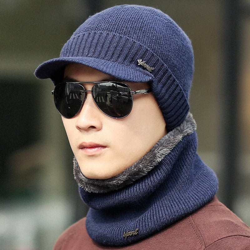 Young man wearing winter knitted hats and sunglasses with a fur-lined neck warmer for style and warmth.