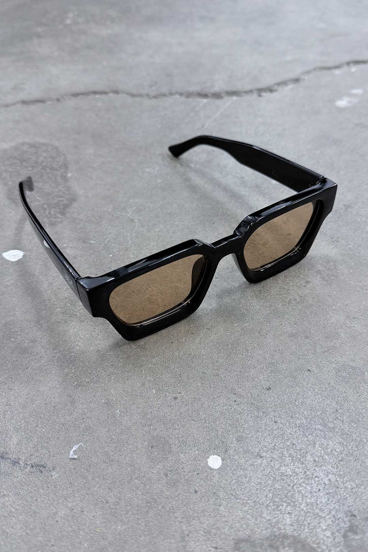 Color Shades - Teddy stylish sunglasses with sleek black frames and brown lenses on a textured surface.