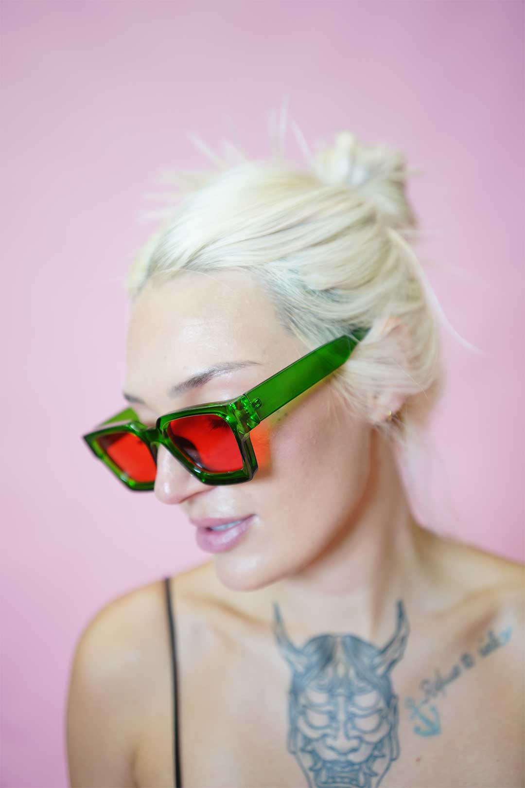 Color Shades - Teddy worn by a model with blonde hair, showcasing edgy green frame and red lenses against pink background.