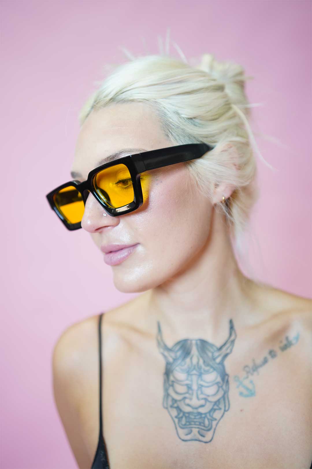 Model wearing Color Shades - Teddy with bold yellow lenses and edgy black frame against a pink background.