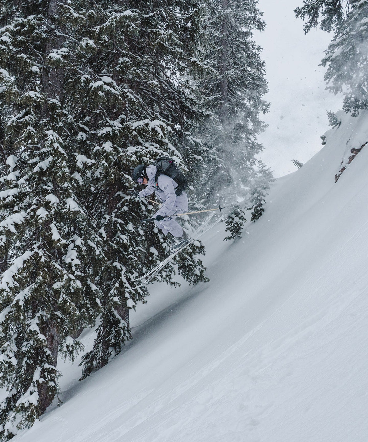 Skier jumping off a snowy slope in a winter landscape, wearing a durable outdoor jacket.