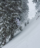 Skier jumping off a snowy slope in a winter landscape, wearing a durable outdoor jacket.