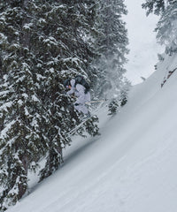 Skier jumping off a snowy slope in a winter landscape, wearing a durable outdoor jacket.