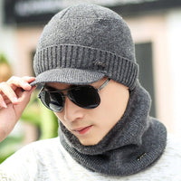 Man wearing a winter knitted hat and scarf, sunglasses on, showcasing winter style and warmth.