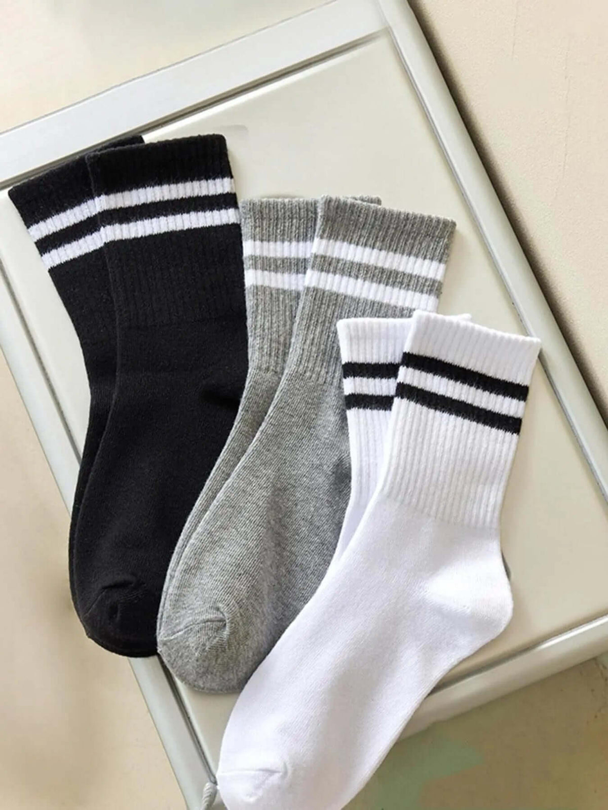 Striped athletic crew socks in black, gray, and white, showcasing stylish design and comfy fit for casual wear.