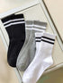 Striped athletic crew socks in black, gray, and white, showcasing stylish design and comfy fit for casual wear.