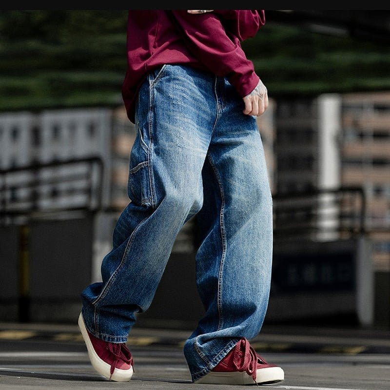 Person wearing blue baggy jeans and red sneakers, showcasing casual streetwear style.