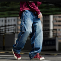 Person wearing blue baggy jeans and red sneakers, showcasing casual streetwear style.