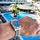 automatic waterproof sports watch for men displayed on wrist by a poolside setting.