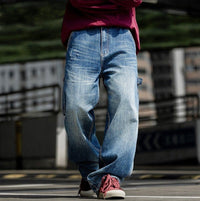 Man wearing relaxed fit blue jeans on urban street.