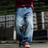 Man wearing relaxed fit blue jeans on urban street.