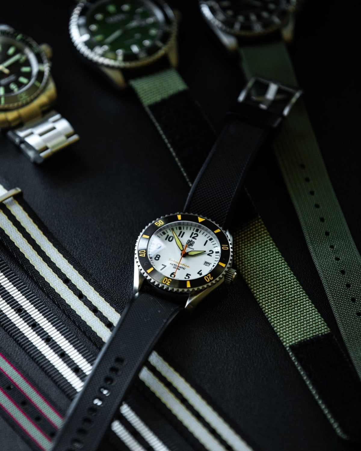 Subnautica Automatic Diver Watch displayed with various straps and other diver watches on a dark surface.