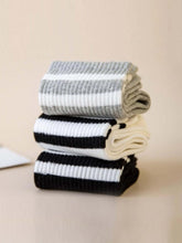striped athletic crew socks womens striped socks in grey, black, and white stacked on a neutral surface