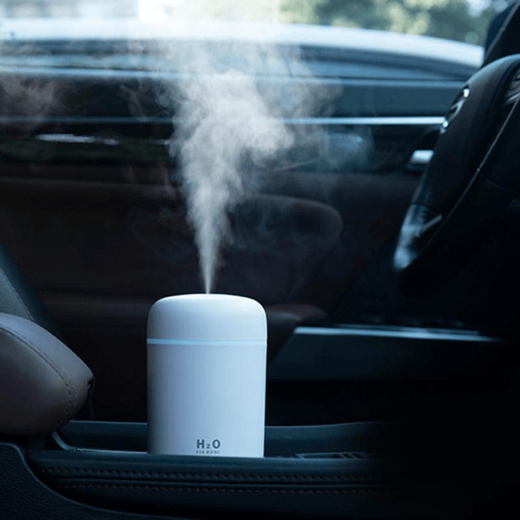 Portable aroma essential oil diffuser in a car, emitting soothing mist for improved air quality.