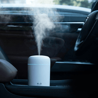 Portable aroma essential oil diffuser in a car, emitting soothing mist for improved air quality.