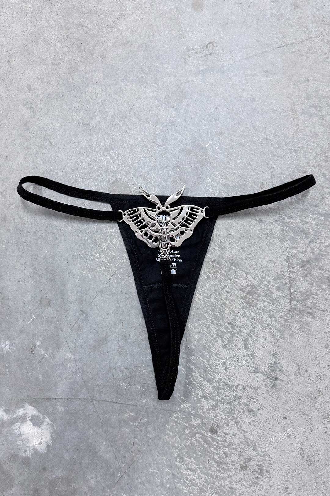 Death Moth Metal Thong - Small with detailed silver moth embellishment on a black fabric background.