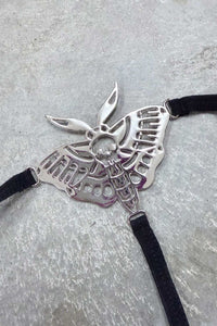 Death Moth Metal Thong - Small featuring a detailed silver moth design with skull and black straps.