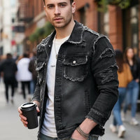 Young man wearing a formal denim jacket while holding a coffee cup in a city setting.