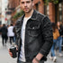 Young man wearing a formal denim jacket while holding a coffee cup in a city setting.