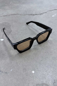 Color Shades - Teddy stylish sunglasses with sleek black frames and brown lenses on a textured surface.